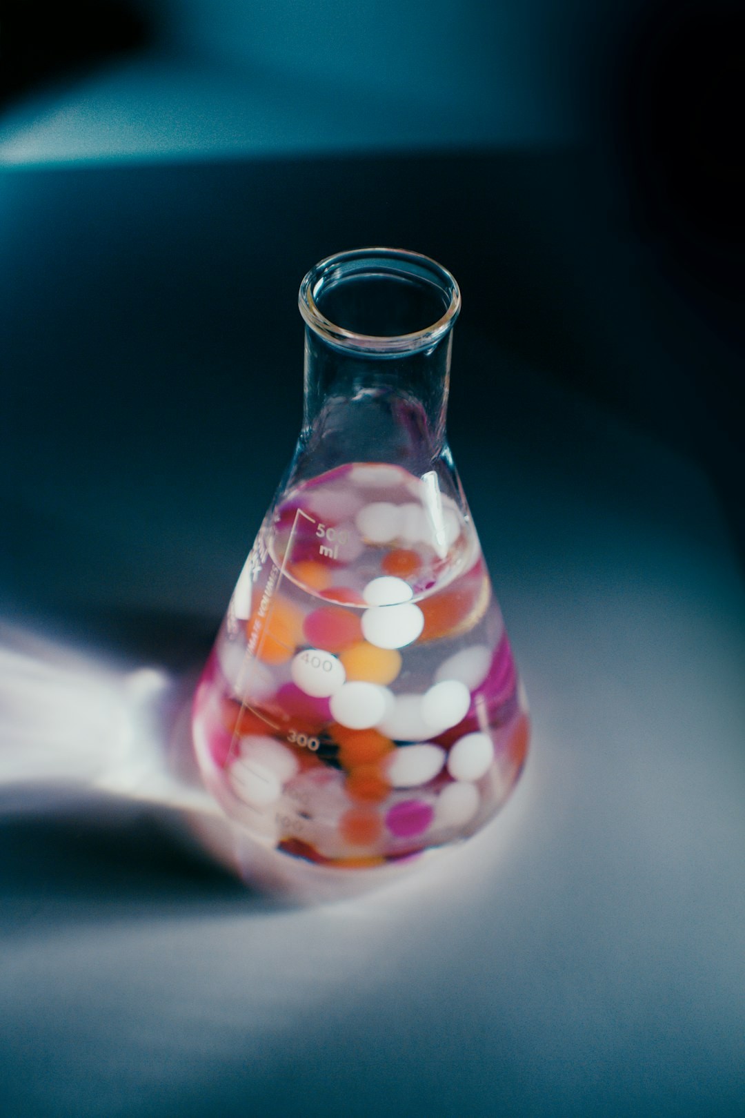 Erlenmeyer flask filled with red, orange and white particles on lab